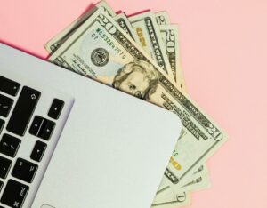 How to get voice over work through freelancer sites, stack of twenty dollar bills under corner of laptop